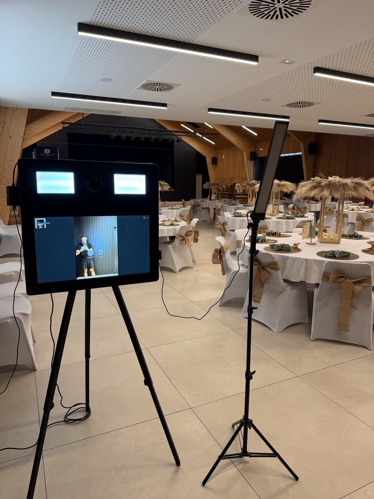 Photobooth classique noir sur trépied dans une salle de réception dressée pour un mariage