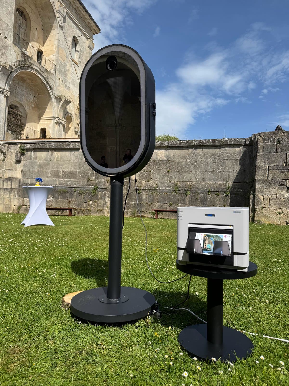Photobooth miroir et son imprimante DNP sur un guéridon, en extérieur devant des ruines