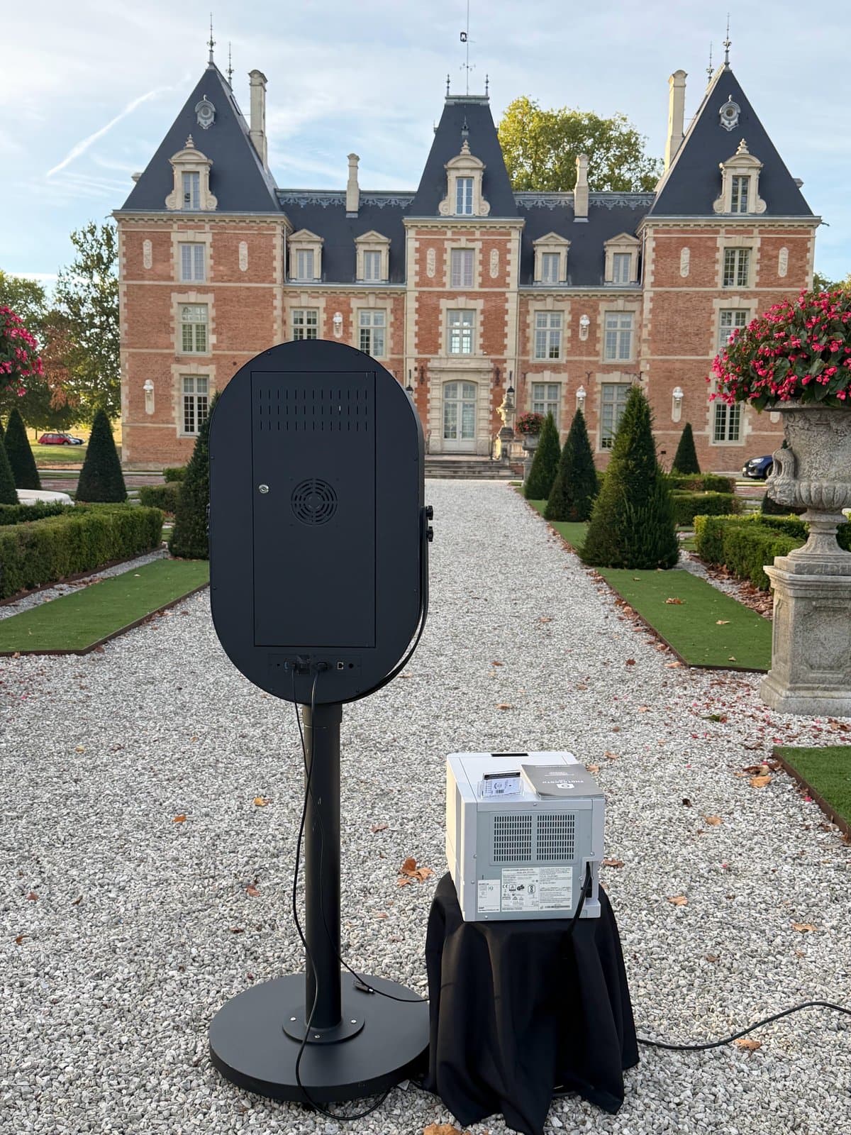 Photobooth miroir et son imprimante dans l'allée d'un château, vus de dos