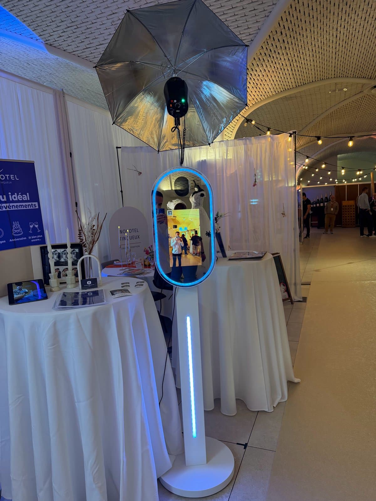 Photobooth miroir compact au contour lumineux bleu, avec flash et parapluie, sur un stand de salon