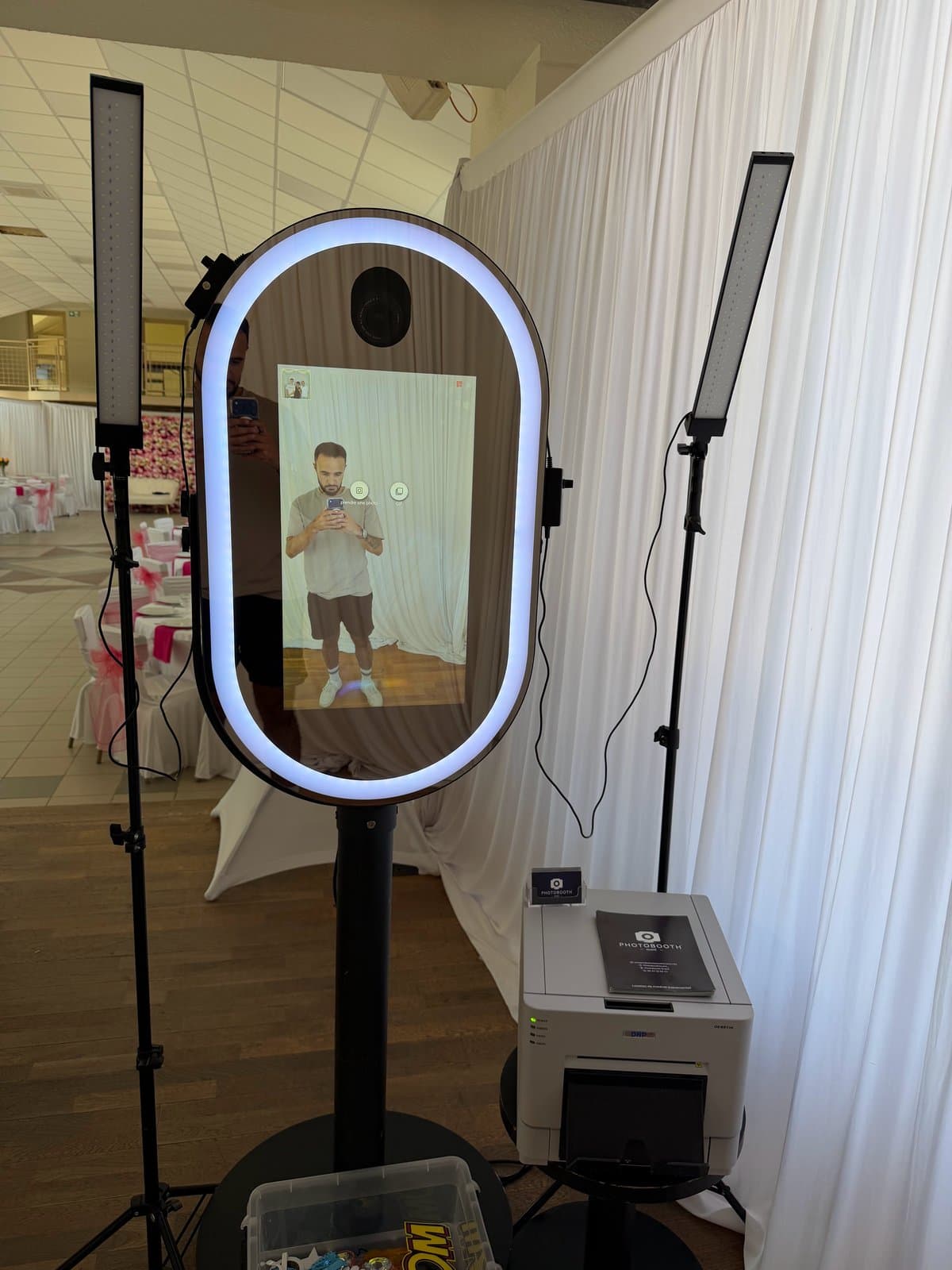 Photobooth miroir au contour lumineux blanc, entre deux éclairages LED, avec son imprimante DNP