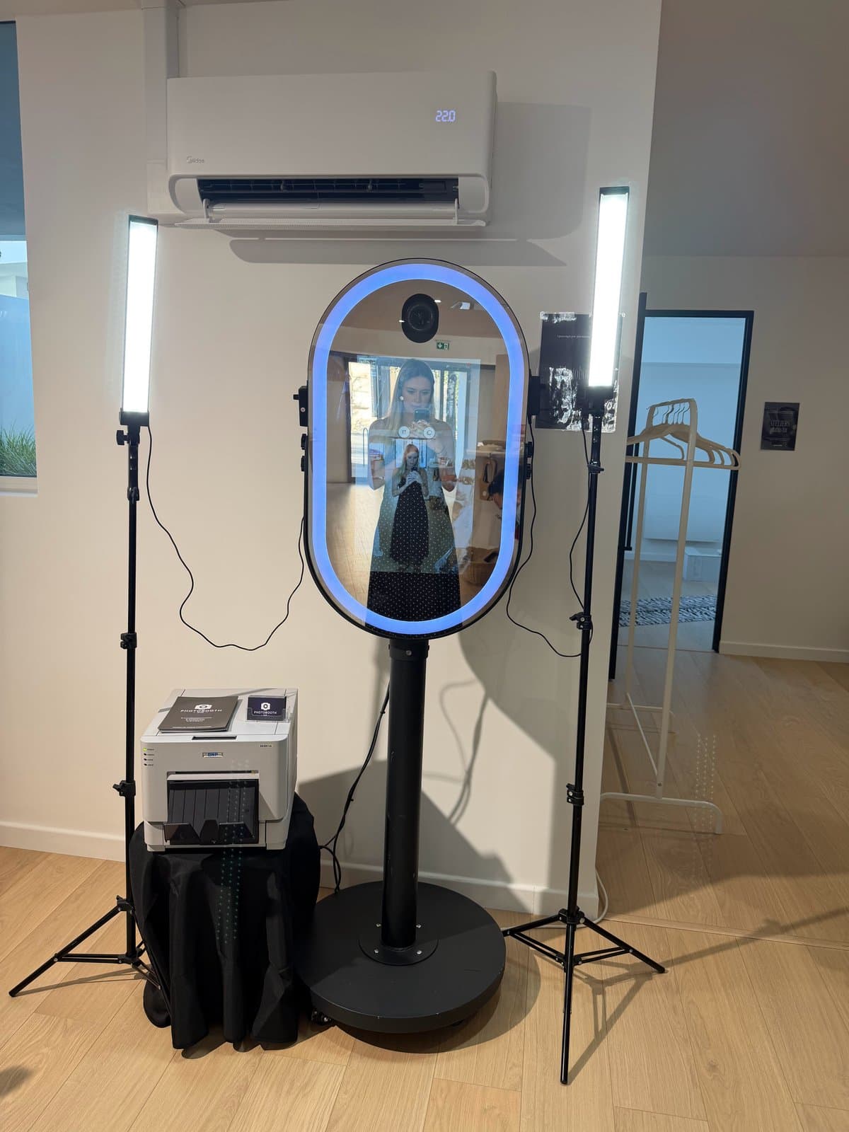 Photobooth miroir au contour lumineux bleu, entre deux éclairages LED, avec son imprimante DNP