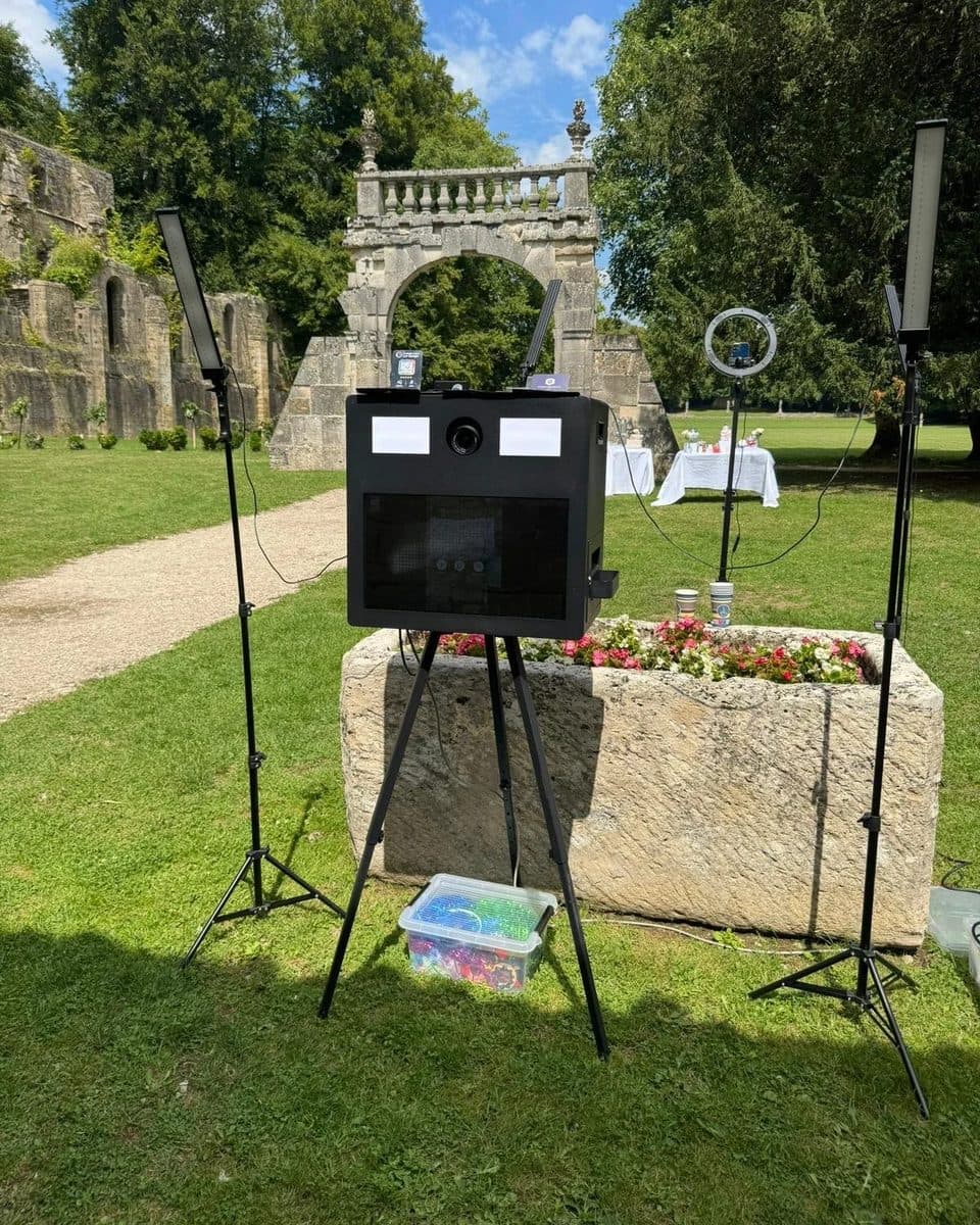 Photobooth classique de Photobooth Event : borne noire sur trépied, entre deux éclairages LED, installée dans le parc d’un château